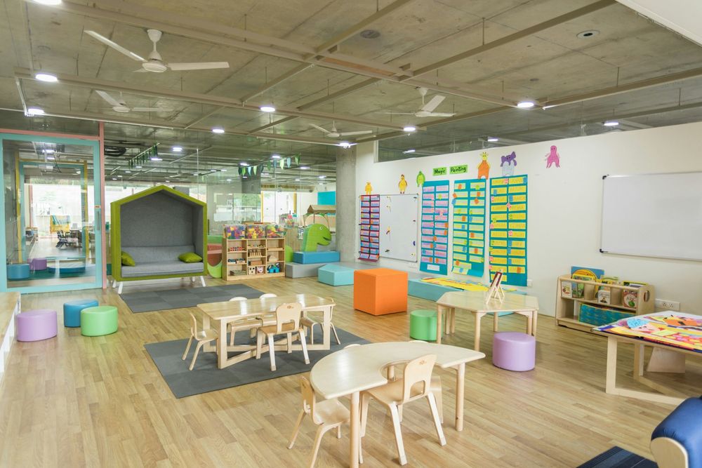 A bright child care classroom with low tables and a reading nook